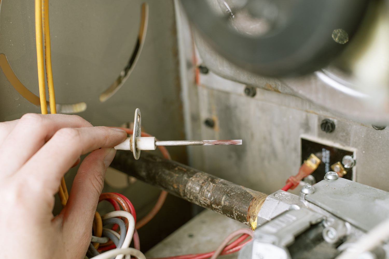 Technician cleaning a furnace flame sensor with steel wool